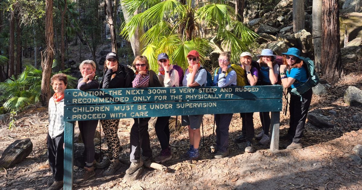Womens hiking group with steep terrain sign