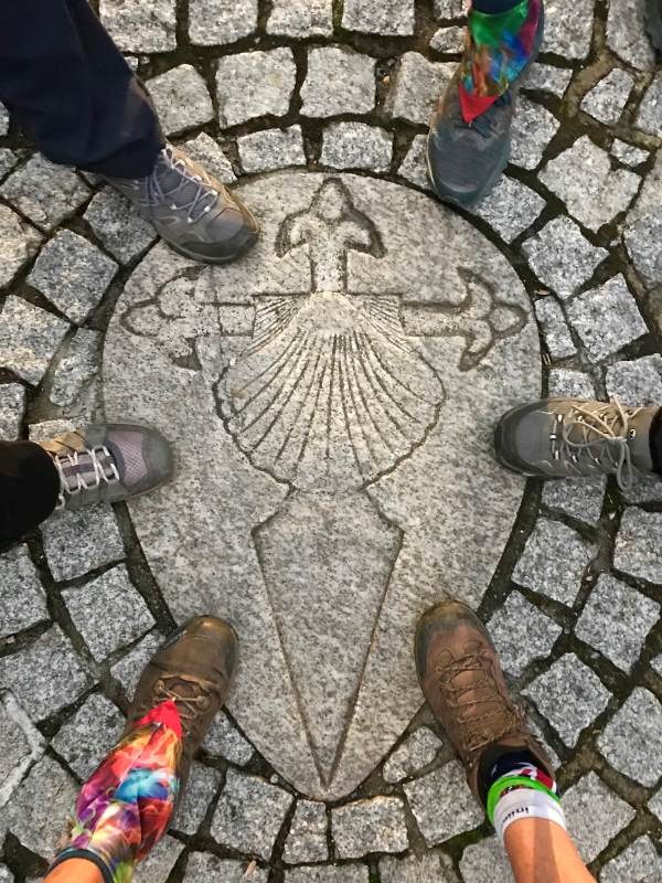 Women putting their hiking boots into the middle of circle witrh the camino logo