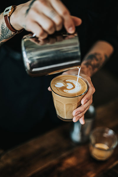 Coffee being poured by a tattooed male barista