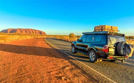 4wd on the road with uluru(ayers rock) in background)