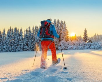 hiker travelling through snow towards sunsrise